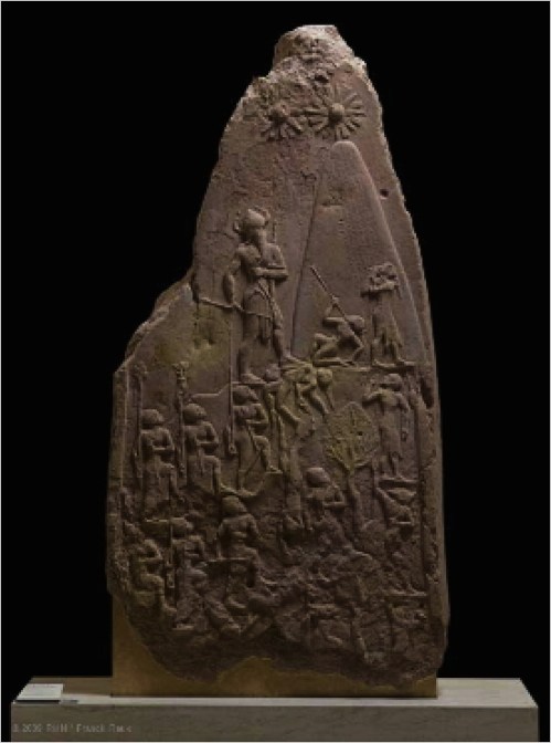 The brilliance of Naram-Sin's reign is reflected in the execution of this stele, which commemorated his victory over Satuni, king of the Lullubi.  The Akkadian army is climbing the steep slopes of the Zagros Mountains, home to the Lullubi. This upward march sweeps aside all resistance. To the right of a line of trees clinging to the mountainside, defeated enemies are depicted in a posture of submission. Those who have been killed are trampled underfoot by the Akkadian soldiers or drop over the precipice. These mountain people are clad in a tunic of hide and wear their long hair tied back. The composition is dominated by the lofty figure of the king, to whom all eyes - those of the Akkadian soldiers and of their Lullubi enemies - are turned. The triumphant sovereign, shown taller than the other men in the traditional manner, leads his army in the attack on the mountain.  He is followed by standard bearers who march before helmeted soldiers carrying bows and axes. Naram-Sin tramples the bodies of his enemies, while a kneeling Lullubi tries to tear out the arrow piercing his throat. Another raises his hands to his mouth, begging the Akkadian king for mercy.  But the conqueror's gaze is directed toward the top of the mountain. Above Naram-Sin, solar disks seem to radiate their divine protection toward him, while he rises to meet them. The Akkadian sovereign wears a conical helmet with horns - a symbol traditionally the privilege of the gods - and is armed with a large bow and an axe. This victorious ascension chiseled in stone thus celebrates a sovereign who considers himself on an equal footing with the gods. In official inscriptions, Naram-Sin's name was therefore preceded with a divine determinative.  He pushed back the frontiers of the empire farther than they had ever been, from Ebla in Syria to Susa in Elam, and led his army 
