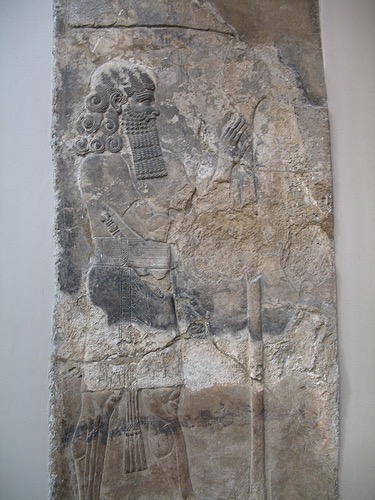 Lahmu, “Hairy,” is a protective and beneficent deity, the first-born son of Apsu and Tiamat. He and his sister Laḫamu are the parents of Anshar and Kishar, the sky father and earth mother, who birthed the gods of the Mesopotamian Pantheon. Laḫmu is depicted as a bearded man with a red sash-usually with three strands- and four to six curls on his head. He is often associated with the Kusarikku or “Bull-Man.” In Sumerian times Laḫmu may have meant “the muddy one”. Lahmu guarded the gates of the Abzu temple of Enki at Eridu. He and his sister Laḫamu are primordial deities in the Babylonian Epic of Creation –Enuma Elis and Lahmu may be related to – or identical with- ‘Lahamu’ one of Tiamat’s Creatures in that epic. http://foundfact.com/portfolio-view/lahmu/#!prettyPhoto http://foundfact.com/library/beings-people-and-gods/page/6/#!prettyPhoto