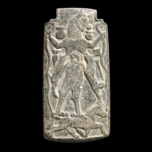 Amulet with a figure of Lamashtu, Mesopotamia, around 800 BC.<br />  A demonic divinity who preys on mothers and children.<br />  This protective image of Lamashtu, a fearsome female divinity of the underworld, was intended to keep evil at bay.<br />  Although she is usually described in modern works as a demon, the writing of her name in cuneiform suggests that in Babylonia and Assyria she was regarded as a kind of goddess.<br />  Unlike the majority of demons, who acted only on the commands of the gods, Lamashtu practised evil apparently for its own sake and on her own initiative. There is a cuneiform incantation on the reverse side of this amulet to frighten her away.<br />  Lamashtu's principal victims were unborn and new-born babies.<br />  Slipping into the house of a pregnant woman, she tries to touch the woman's stomach seven times to kill the unborn baby, or she kidnaps the child.<br />  Magical measures against Lamashtu included wearing a bronze head of Pazuzu. Some plaques show a bedridden man rather than a pregnant woman, so in some contexts Lamashtu is considered a bringer of disease.<br />  Lamashtu is described in texts as having the head of a lion, the teeth of a donkey, naked breasts, a hairy body, stained hands, long fingers, long finger nails, and the talons of a bird.<br />  Plaques also show her suckling a piglet and a whelp while she holds snakes in her hands, as in this case.<br />  She stands on her sacred animal, the donkey, which is sometimes shown in a boat, riding through the underworld.<br />  H.W.F. Saggs, Babylonians (London, The British Museum Press, 1995)<br />  J. Black and A. Green, Gods, Demons and Symbols of Ancient Mesopotamia (London, The British Museum Press, 1992)<br />  http://utpress.utexas.edu/index.php/books/blagop#sthash.psbzCU3E.dpuf<br />  http://www.britishmuseum.org/explore/highlights/highlight_objects/me/a/amulet_with_figure_of_lamashtu.aspx