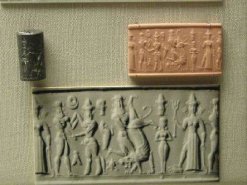 At far left, Enkidu grapples with Gilgamesh, wearing a horned crown of divinity. Enkidu fights a bull in the center, and a goddess, Ishtar, wearing a crown of divinity and weapons at her back, flanks a small female figure, possibly the priestess Shamhat, who tamed Enkidu. https://en.wikipedia.org/wiki/Shamhat